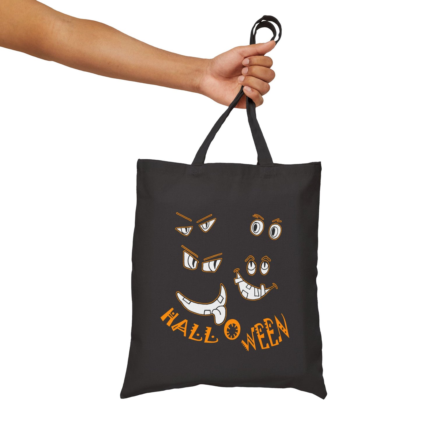 Halloween cut out faces peer out of a Black Cotton Canvas Tote Bag by artist Marie Frederique